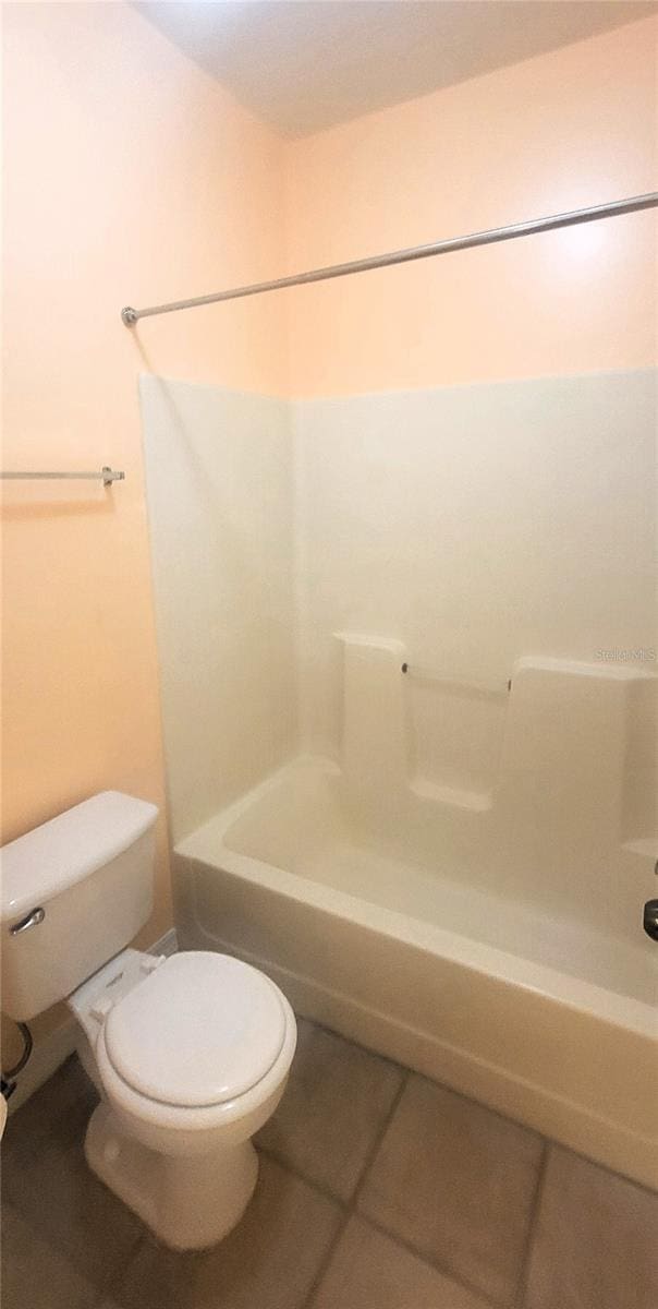 bathroom featuring tile patterned flooring, toilet, and shower / bath combination