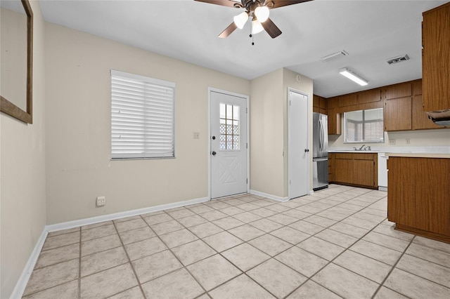 kitchen featuring light tile patterned flooring, sink, stainless steel refrigerator, dishwasher, and ceiling fan