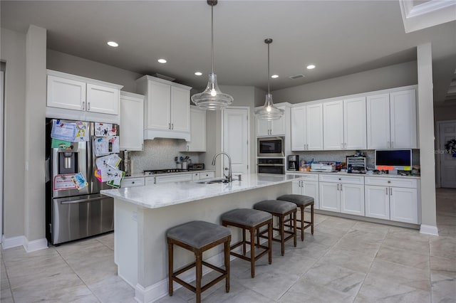 kitchen with white cabinetry, appliances with stainless steel finishes, a breakfast bar area, and a center island with sink