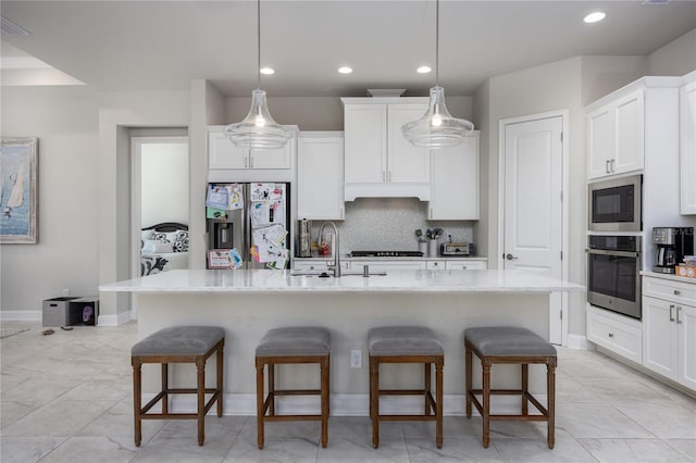 kitchen featuring a kitchen island with sink, decorative light fixtures, stainless steel appliances, and a kitchen bar