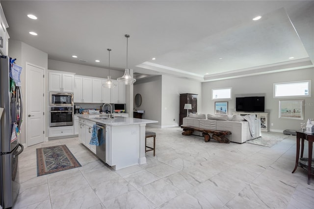 kitchen featuring sink, white cabinetry, hanging light fixtures, an island with sink, and stainless steel appliances