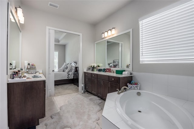 bathroom with tile patterned floors, vanity, and tiled bath