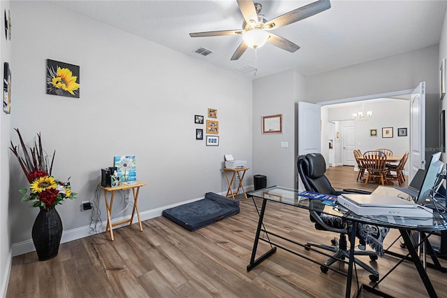 office space featuring ceiling fan with notable chandelier and wood-type flooring