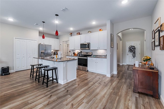 kitchen featuring white cabinetry, stainless steel appliances, an island with sink, and a breakfast bar area