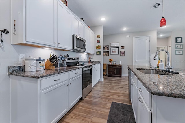 kitchen with dark stone countertops, sink, stainless steel appliances, and white cabinets