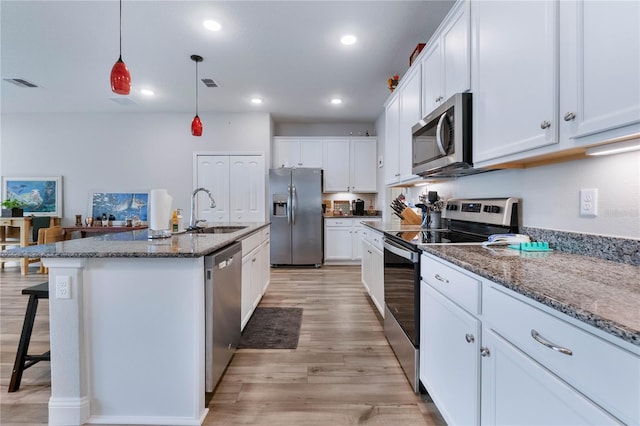 kitchen featuring pendant lighting, sink, stainless steel appliances, an island with sink, and white cabinets