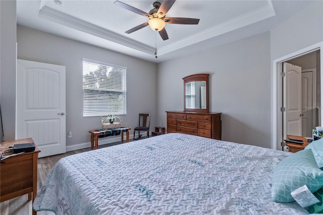 bedroom with hardwood / wood-style flooring, ornamental molding, a raised ceiling, and ceiling fan