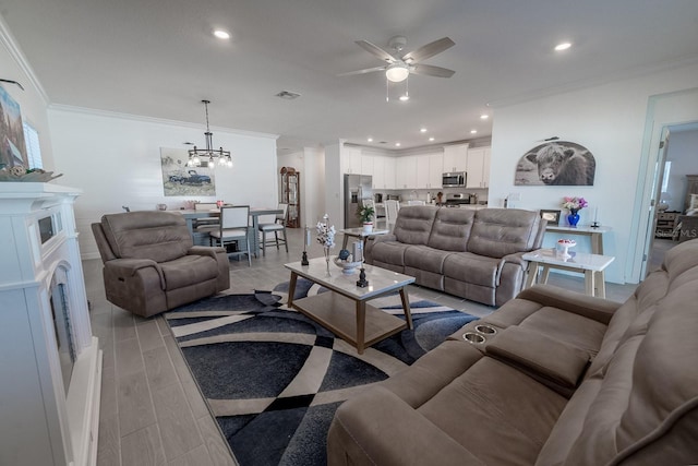 living room featuring crown molding, a fireplace, and ceiling fan with notable chandelier