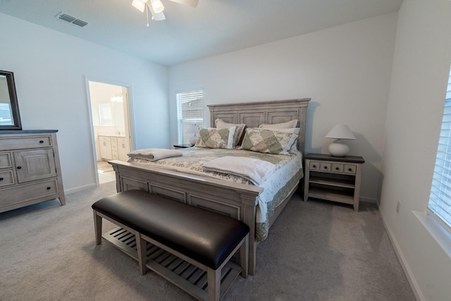 bedroom featuring ensuite bathroom, light colored carpet, and ceiling fan