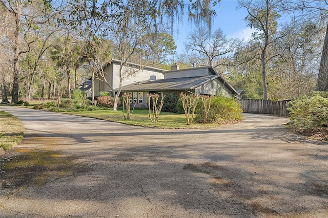 view of home's exterior with fence, a chimney, and a lawn