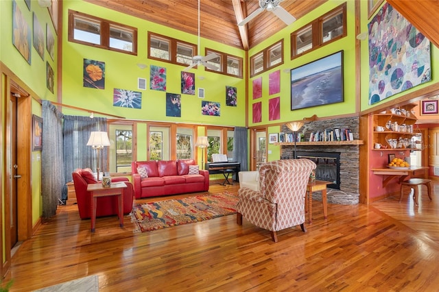 living room featuring hardwood / wood-style floors, a stone fireplace, and ceiling fan