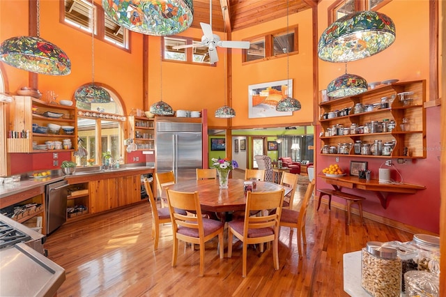 dining space with sink, a towering ceiling, light hardwood / wood-style flooring, and ceiling fan