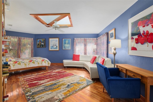 bedroom with dark hardwood / wood-style flooring, a skylight, and ceiling fan