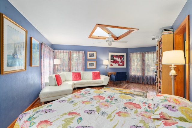 living room featuring hardwood / wood-style floors, a skylight, and ceiling fan