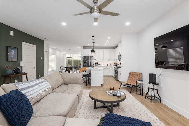 living room with ceiling fan, sink, and light hardwood / wood-style floors