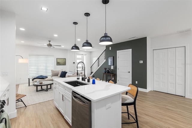 kitchen featuring sink, white cabinetry, a center island with sink, decorative light fixtures, and stainless steel dishwasher