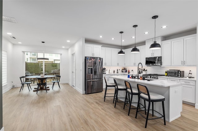 kitchen with stainless steel appliances, pendant lighting, and white cabinets