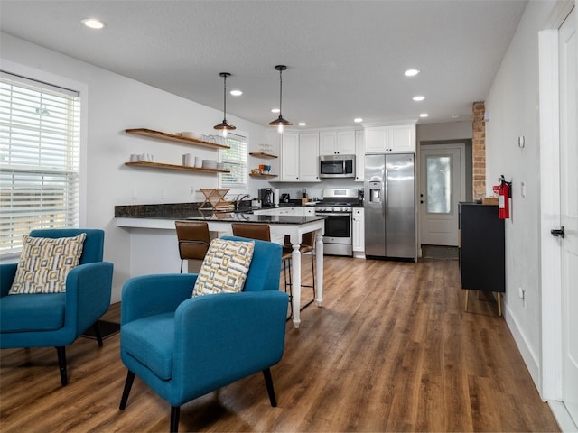 kitchen with a breakfast bar, appliances with stainless steel finishes, kitchen peninsula, pendant lighting, and white cabinets