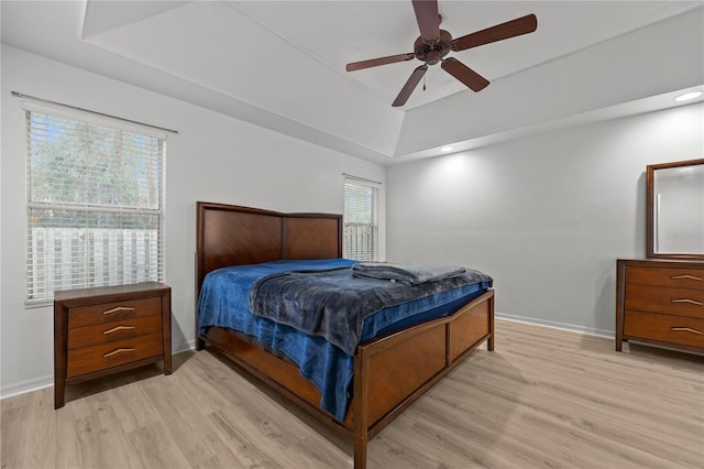 bedroom featuring ceiling fan, a tray ceiling, and light hardwood / wood-style floors