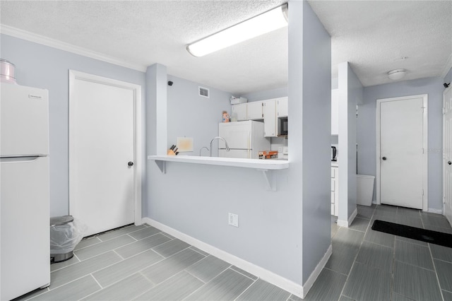 kitchen featuring white refrigerator, kitchen peninsula, a textured ceiling, and white cabinets