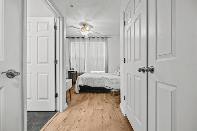 bedroom featuring ceiling fan, light hardwood / wood-style flooring, and a textured ceiling