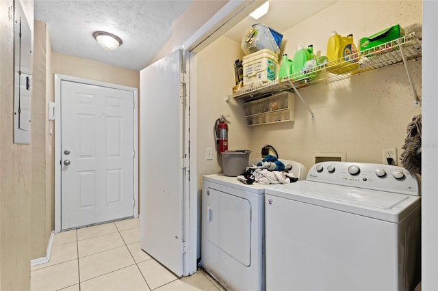 clothes washing area with light tile patterned floors, a textured ceiling, independent washer and dryer, and electric panel