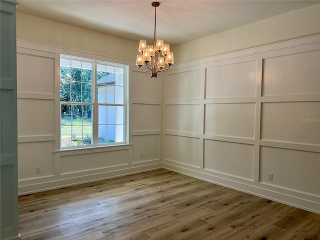 unfurnished dining area featuring a chandelier and light hardwood / wood-style flooring