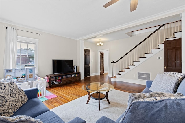 living room featuring hardwood / wood-style flooring, ornamental molding, and ceiling fan with notable chandelier