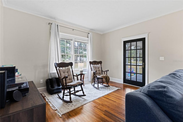 living area with crown molding, hardwood / wood-style flooring, and a healthy amount of sunlight