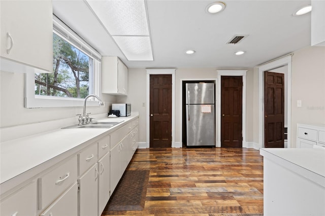 kitchen featuring white cabinetry, stainless steel fridge, dark hardwood / wood-style flooring, and sink