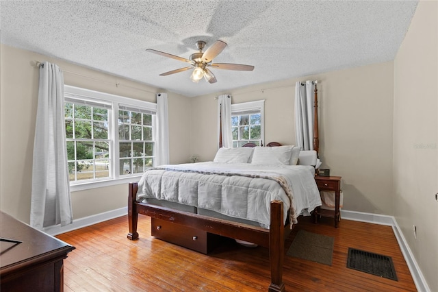 bedroom featuring ceiling fan, wood-type flooring, and a textured ceiling