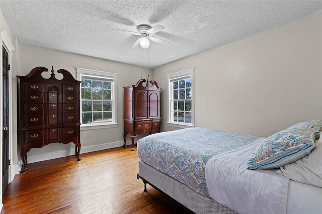 bedroom featuring ceiling fan, wood-type flooring, and a textured ceiling