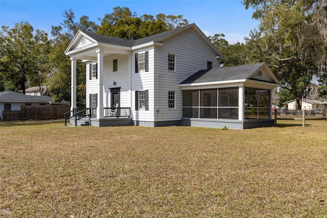 back of house featuring a sunroom and a lawn