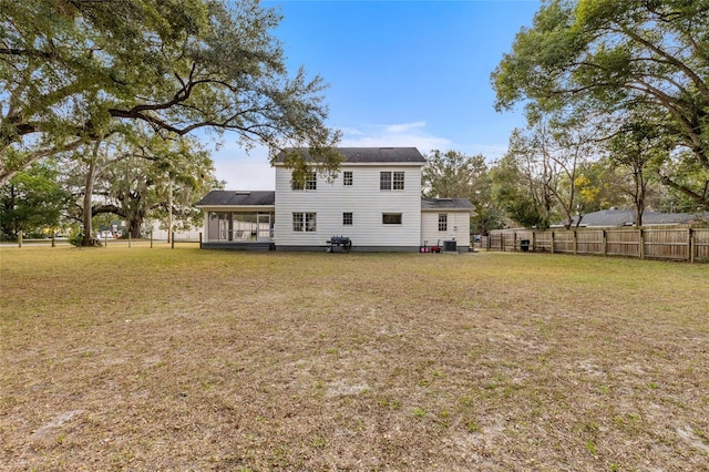 rear view of property with cooling unit and a lawn