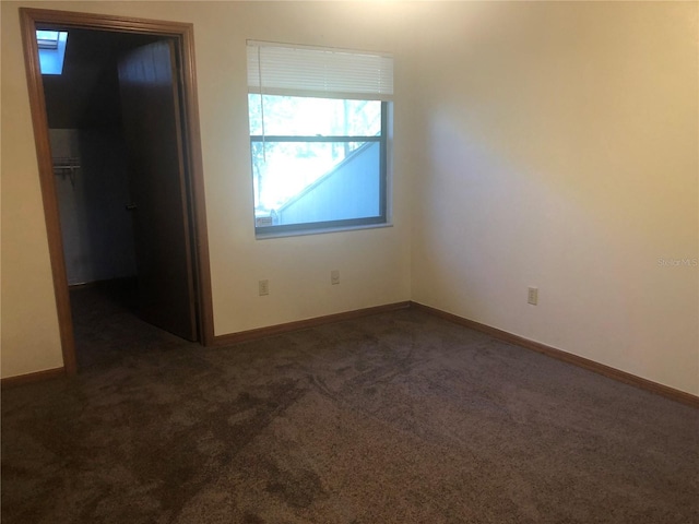 spare room with dark colored carpet