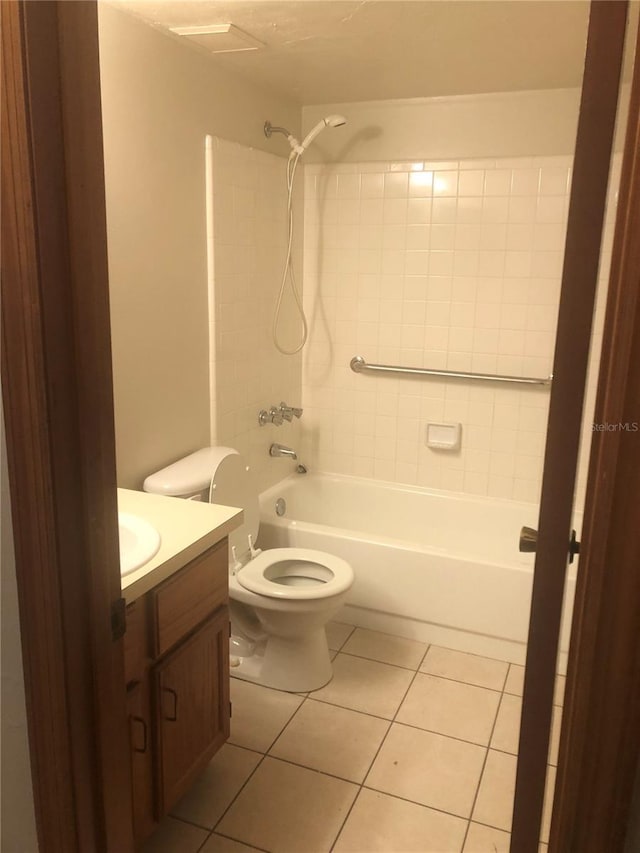 full bathroom featuring tiled shower / bath, vanity, toilet, and tile patterned flooring