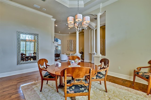 dining space with ornate columns, crown molding, and hardwood / wood-style flooring