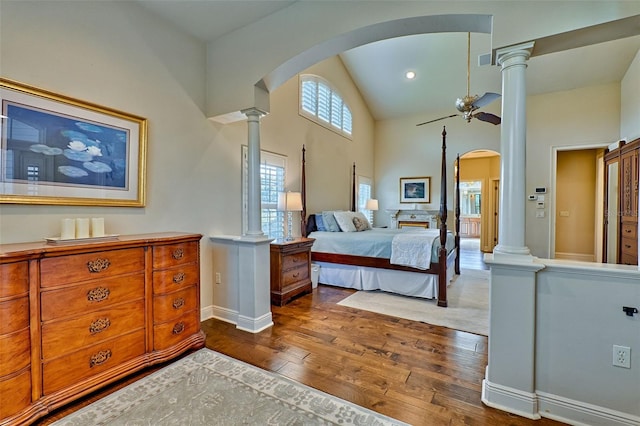 bedroom with hardwood / wood-style floors, decorative columns, and high vaulted ceiling