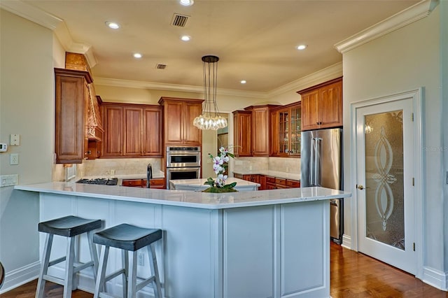 kitchen with pendant lighting, wood-type flooring, a kitchen bar, kitchen peninsula, and stainless steel appliances