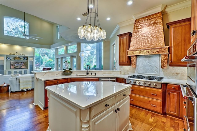 kitchen with appliances with stainless steel finishes, a center island, sink, and light stone countertops