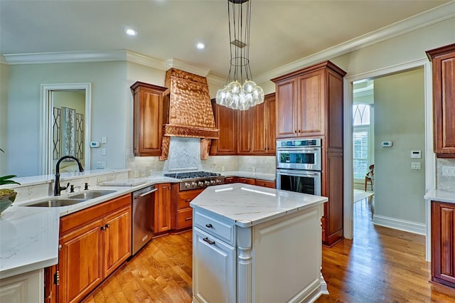 kitchen with sink, appliances with stainless steel finishes, a kitchen island, decorative light fixtures, and custom exhaust hood