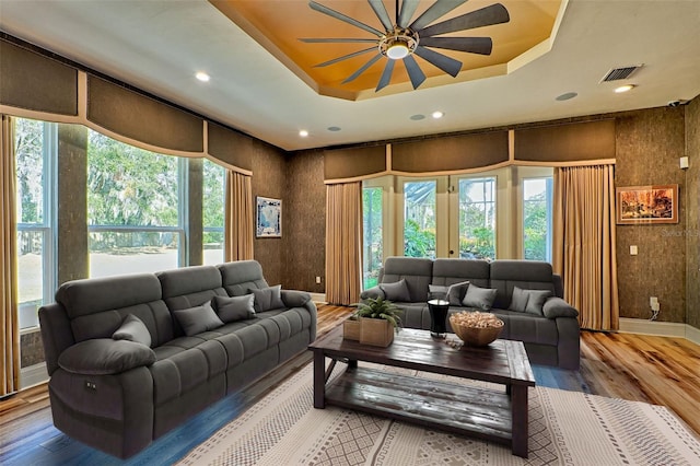 living room featuring hardwood / wood-style flooring, a raised ceiling, and a wealth of natural light