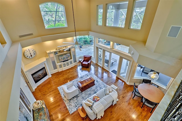 living room featuring hardwood / wood-style floors, a towering ceiling, and ceiling fan