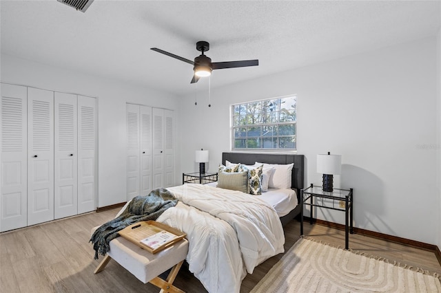 bedroom featuring multiple closets, ceiling fan, a textured ceiling, and light wood-type flooring