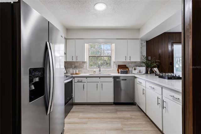 kitchen with appliances with stainless steel finishes, sink, white cabinets, and decorative backsplash