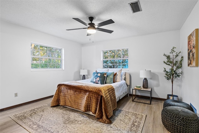 bedroom with ceiling fan, wood-type flooring, and a textured ceiling