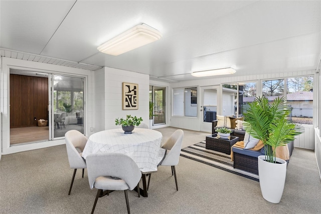 carpeted dining space with wood walls