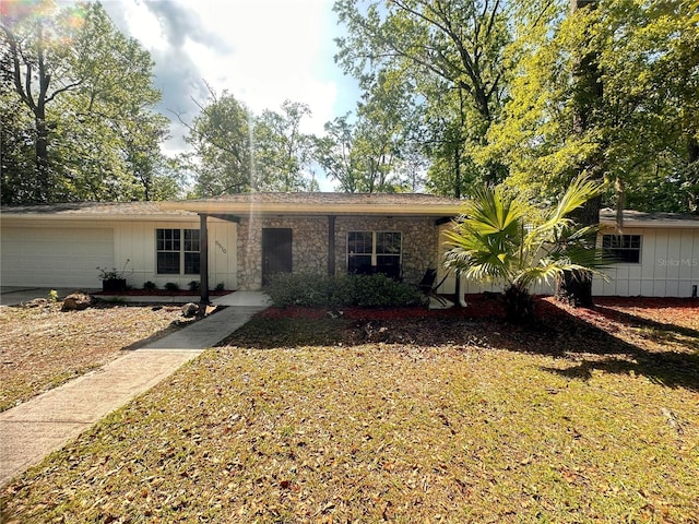 single story home featuring stone siding, an attached garage, concrete driveway, and board and batten siding
