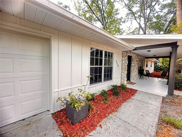 property entrance featuring stone siding, board and batten siding, and a garage