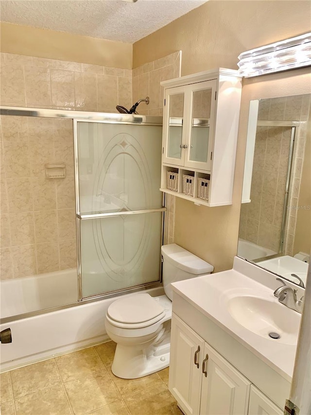 full bathroom featuring bath / shower combo with glass door, vanity, toilet, tile patterned floors, and a textured ceiling